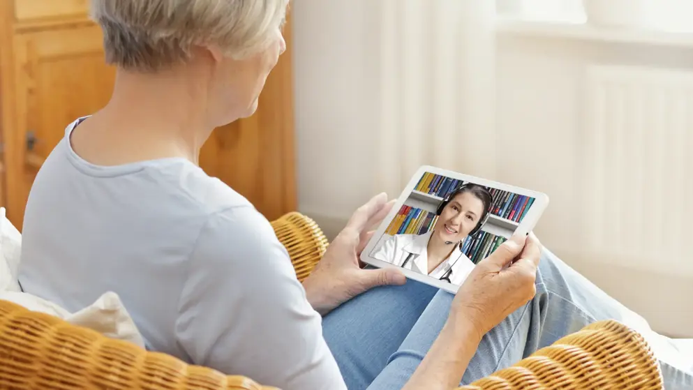 telemedicine concept, woman with grey hair, with tablet pc during an online consultation with her doctor in her living room