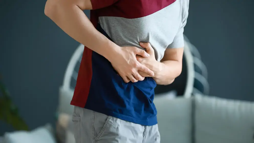 Young man clutching his side with liver or kidney pain