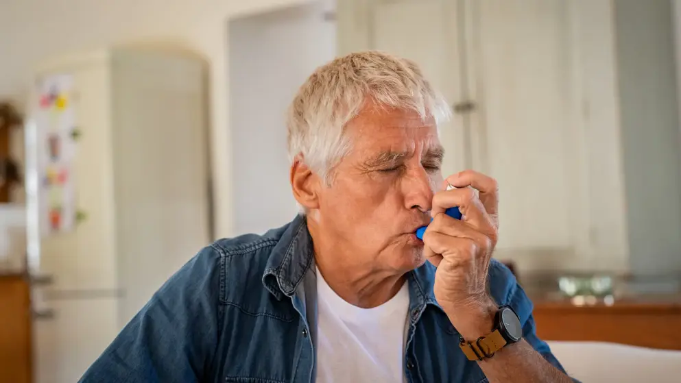 Older man with asthma using an inhaler