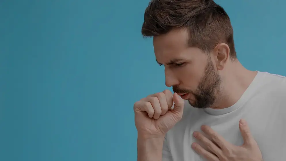 A young bearded man coughing on a blue background