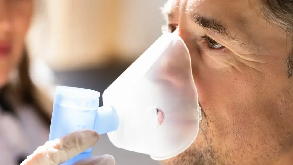 A young man using a nebuliser to assist with COPD