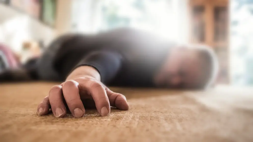 A foreground focus of a man's hand as he lays collapsed after a seizure; his head and body are blurred in the background