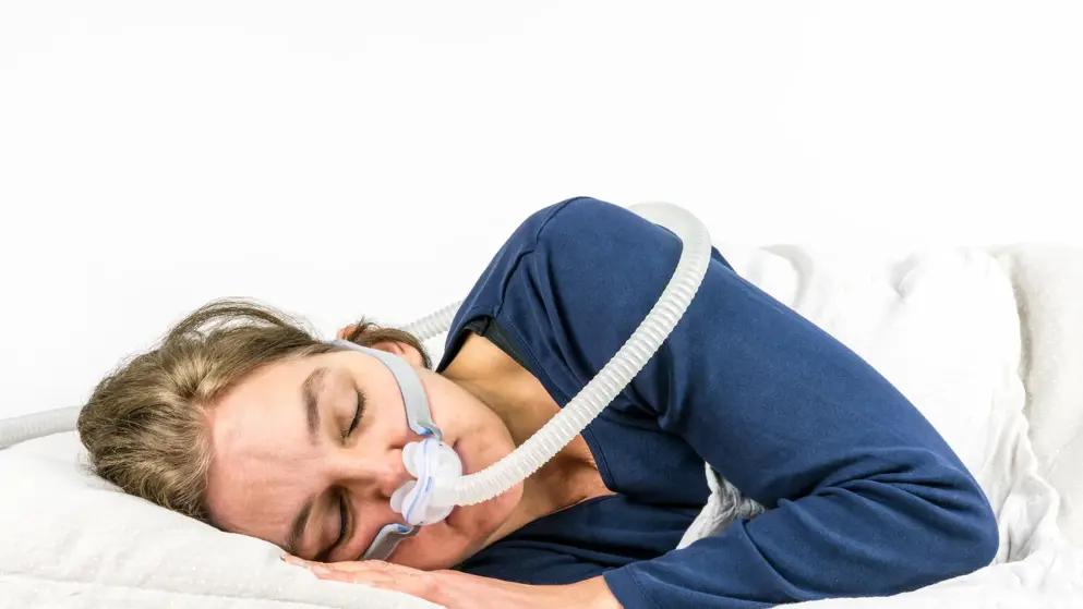 Woman sleeping on her side with a CPAP machine over her nose and mouth